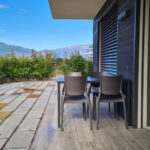 Table extérieure avec chaises, terrasse couverte et cour.